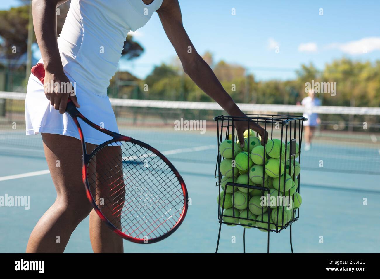 Section médiane d'une joueuse afro-américaine pratiquant le tennis sur le court par beau temps Banque D'Images
