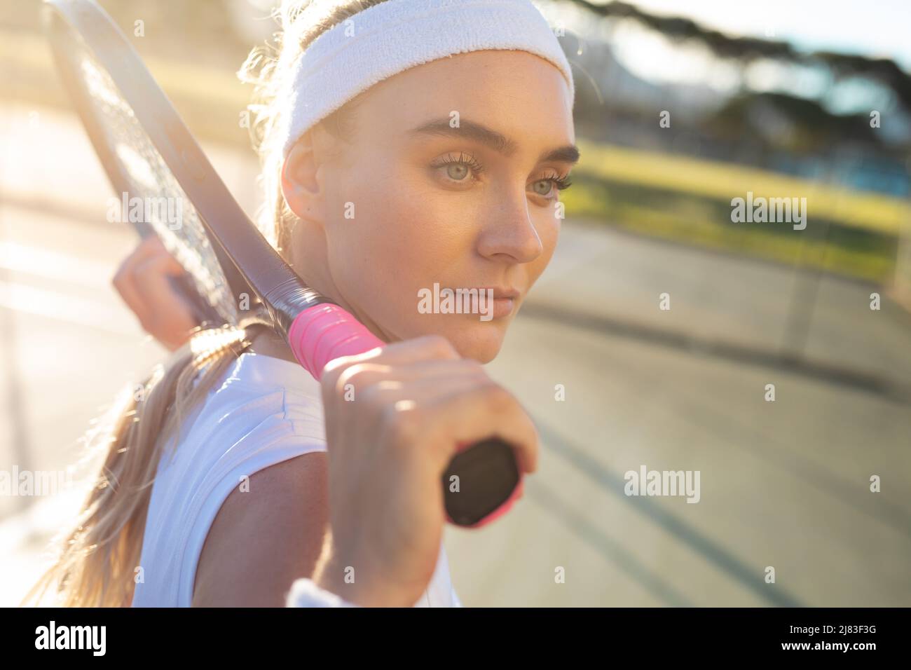 Vue latérale d'une jeune belle joueuse de tennis caucasienne avec raquette autour du cou sur le court Banque D'Images