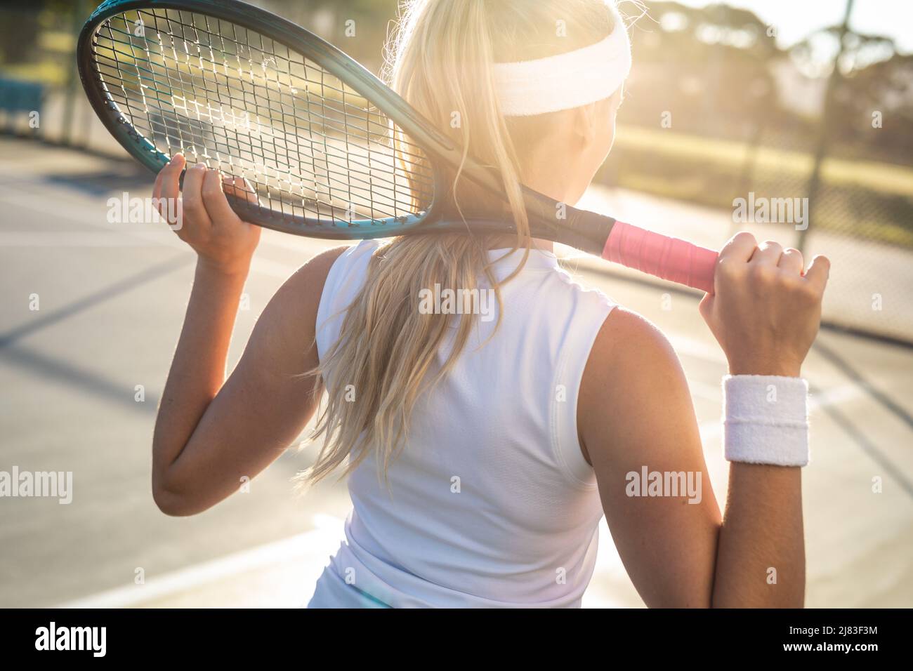 Vue arrière d'une jeune femme blonde de race blanche avec raquette de tennis autour du cou sur le court Banque D'Images