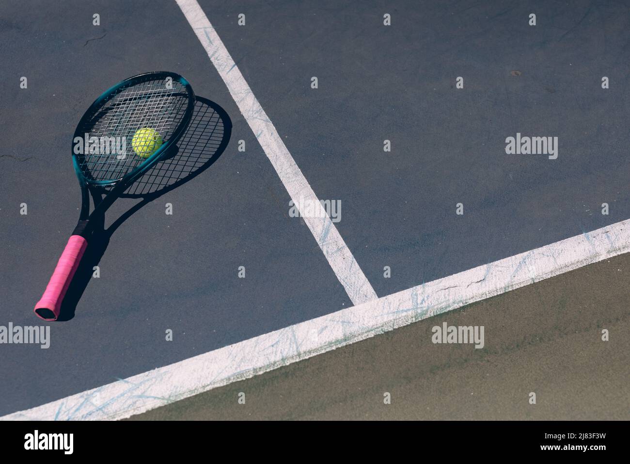 Vue en grand angle de la raquette de tennis sur le ballon et le court avec des lignes pendant la journée ensoleillée Banque D'Images