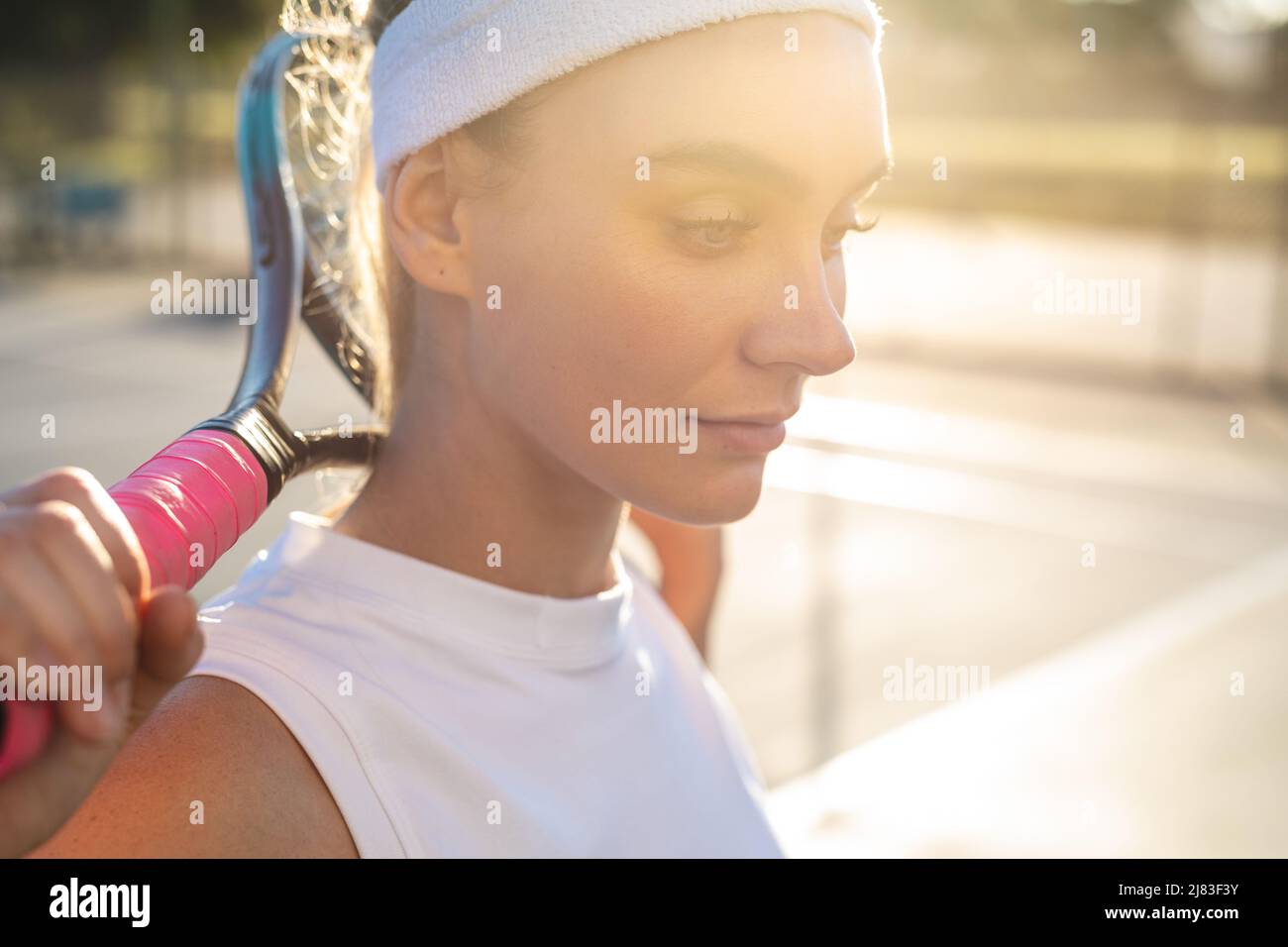 Jeune femme de race blanche, attentionnés, avec une raquette de tennis autour du cou, regardant vers le bas Banque D'Images