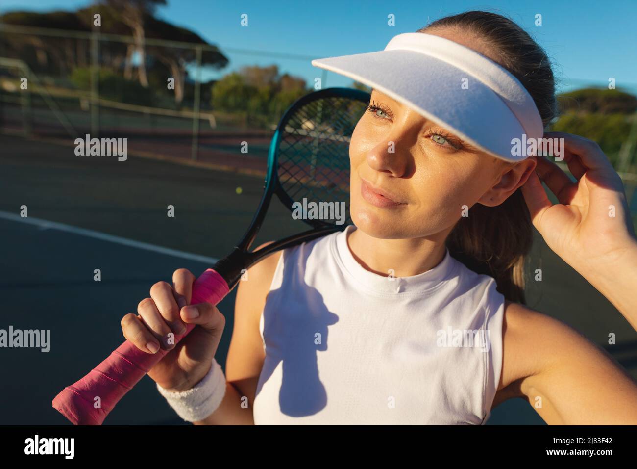 Belle jeune femme joueur de tennis caucasien portant une casquette de  visière tenant la raquette sur le court Photo Stock - Alamy