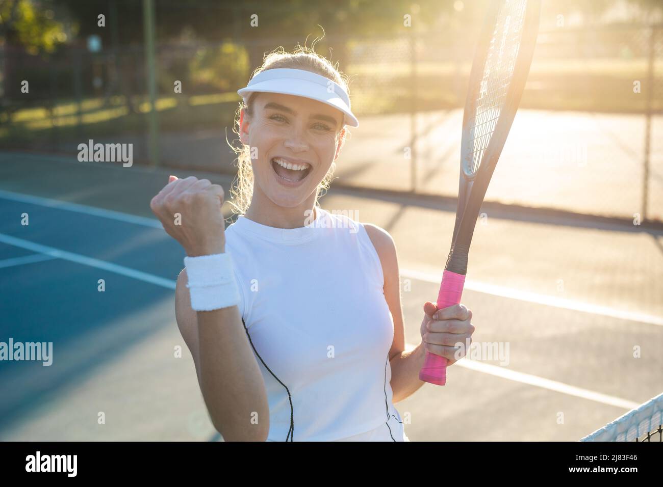 Portrait d'une jeune heureuse belle femme caucasienne célébrant le jeu de tennis gagnant avec le poing Banque D'Images