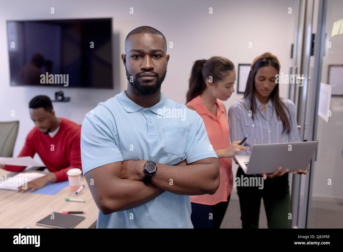 Portrait d'un jeune homme d'affaires afro-américain avec des armes croisées contre ses collègues dans la salle de réunion Banque D'Images