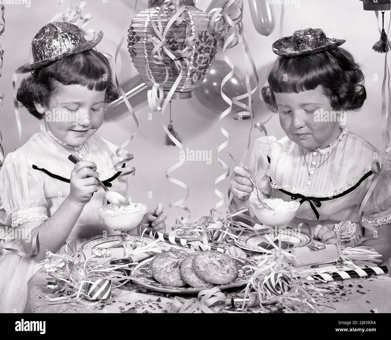 1950S FRECKLE FACE TWIN FILLES MANGER GLACE FÊTE CHAPEAUX BANDEROLES ANNIVERSAIRE CÉLÉBRATION DANS LES ROBES ASSORTIES MAIS DIFFÉRENTS CHAPEAUX - F501 HAR001 HARS HEUREUX JOIE STYLE DE VIE SATISFACTION CÉLÉBRATION FEMMES STREAMERS STUDIO PRISE DE VUE SANTÉ MAISON VIE COPIE ESPACE AMITIÉ DEMI-LONGUEUR MATCH COOKIES FRECKLES FRÈRES ET SŒURS B&W CORRESPONDANT MÊME BONHEUR GAIES FÊTES GAIES FRÈRES ET SŒURS CONNEXION CONCEPTUEL CONSOMMER JOYEUSE GLACE LOOK-SEMBLABLES LES JEUNES DE CROISSANCE À DOUBLE FACE À LA RÉTRODIFFUSION RESSEMBLENT À DES GROUPES DE POPULATION NOIR ET BLANC DE RACE BLANCHE CLONE ETHNIQUE HAR001 À L'ANCIENNE Banque D'Images