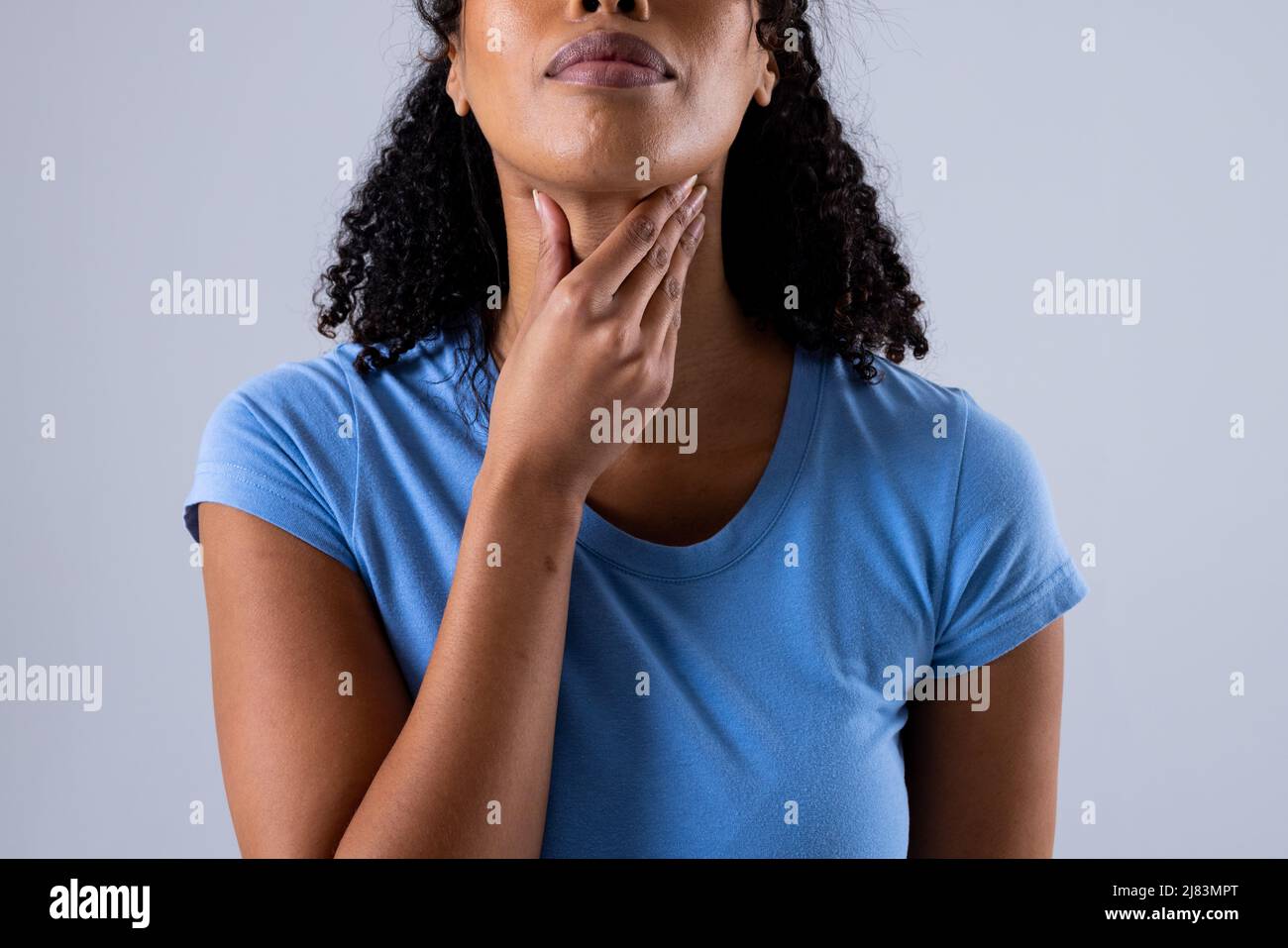 Section médiane d'une femme africaine américaine de taille moyenne touchant la gorge douloureuse sur fond blanc Banque D'Images