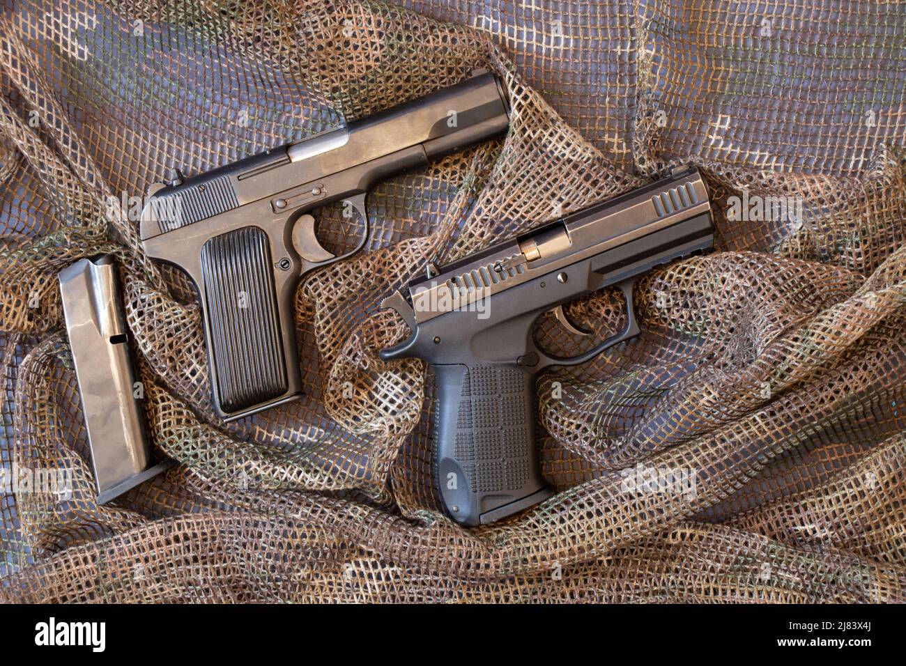 Deux pistolets de combat se trouvent sur un filet protecteur de camouflage, arme militaire, pistolet Banque D'Images