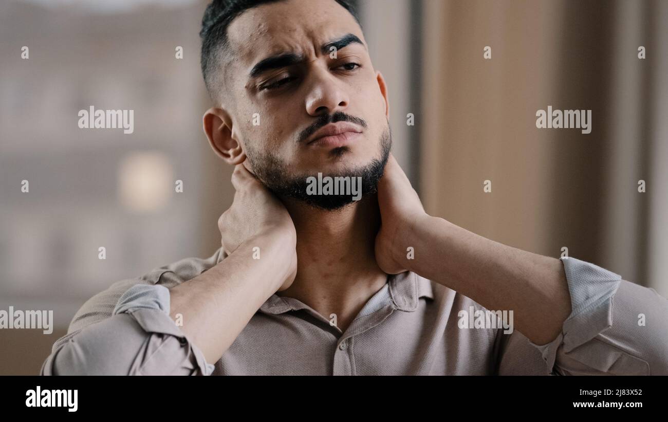Fatigué hispanique épuisé homme d'affaires employé souffrant de la tension musculaire ayant le cou douloureux en raison des heures de travail supplémentaires dans le bureau submergé Banque D'Images