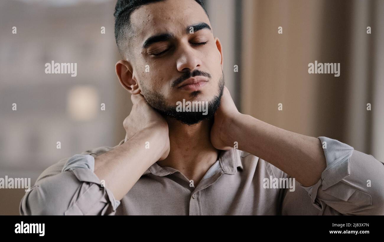 Fatigué hispanique épuisé homme d'affaires employé souffrant de la tension musculaire ayant le cou douloureux en raison des heures de travail supplémentaires dans le bureau submergé Banque D'Images