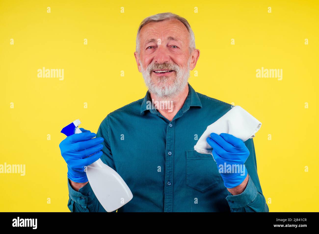 Portrait d'un homme avec une serviette et un spray prêt à nettoyer les fenêtres sur fond jaune studio Banque D'Images