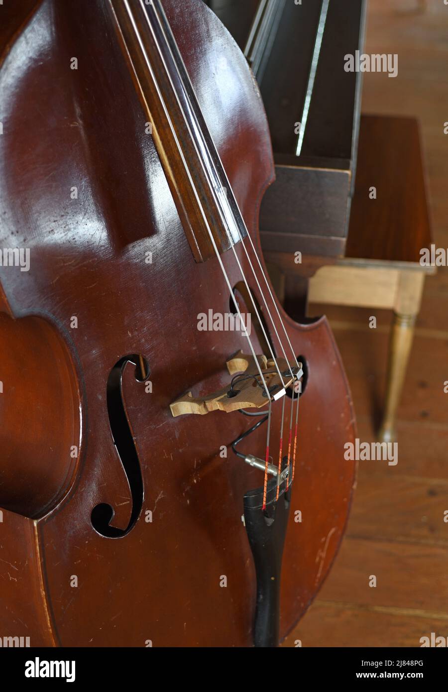 Un vieux violoncelle avec un piano en arrière-plan Banque D'Images