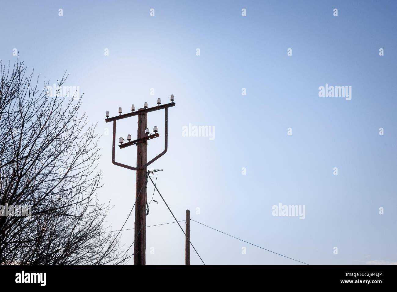 Photo d'un ancien poteau en bois, avec des câbles d'électricité autour, pris au cours d'un après-midi ensoleillé avec ses anciens et anciens câbles d'alimentation. Banque D'Images