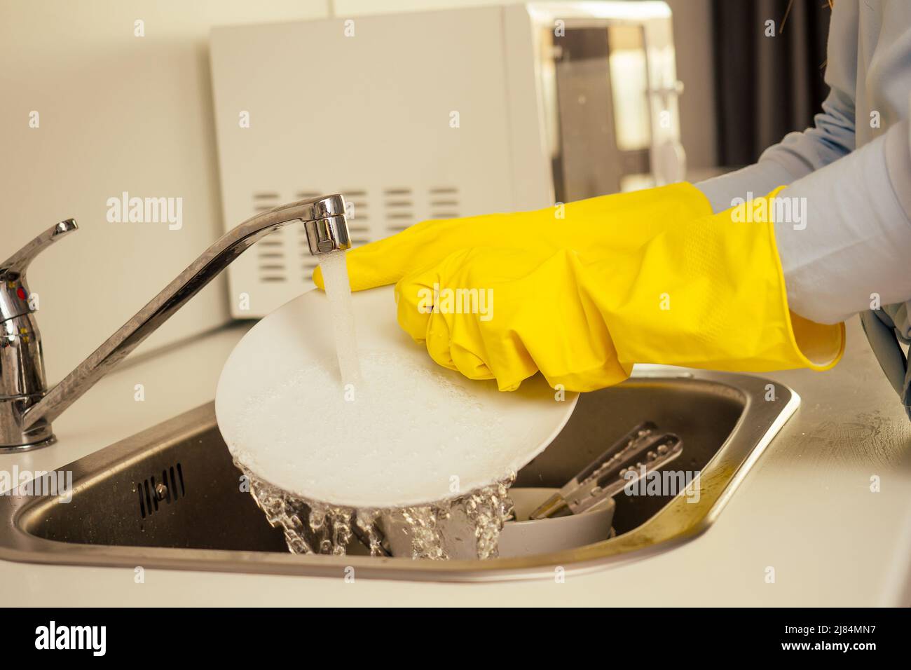 malheureux gingembre rougeâtre belle femme portant le gant jaune et la pile de lavage montagnes de plats sales: tasses, poêle, casserole dans la cuisine Banque D'Images
