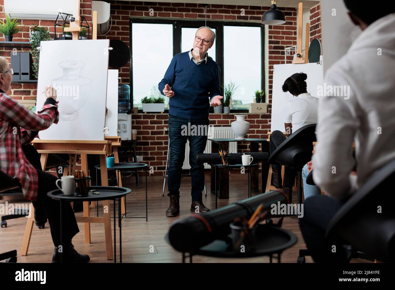 Équipe multiethnique modèle de vase d'esquisse sur toile blanche pendant le cours de créativité apprendre comment ro dessiner pour la croissance personnelle. Homme enseignant expliquant la technique de dessin aux élèves. Concept d'activité créative Banque D'Images