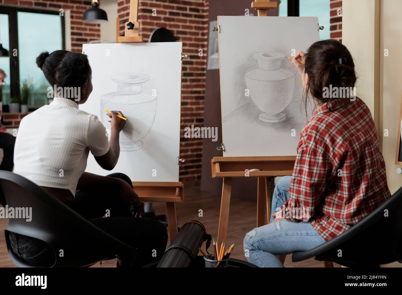 L'équipe Multuethnique travaille au projet créatif dessin vase croquis sur toile blanche en utilisant la technique d'illustration. Les étudiantes qui suivent la leçon d'esquisse apprennent de nouvelles compétences artistiques pour la croissance personnelle Banque D'Images