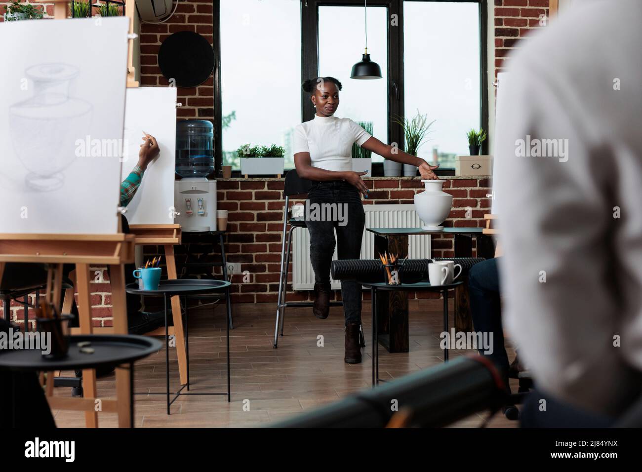 Professeur de peintre enseignant d'art élèves comment développer des compétences artistiques pendant l'atelier de création. Vase d'esquisse de diverses équipes sur toile blanche utilisant la technique graphique travaillant à l'illustration de dessin Banque D'Images