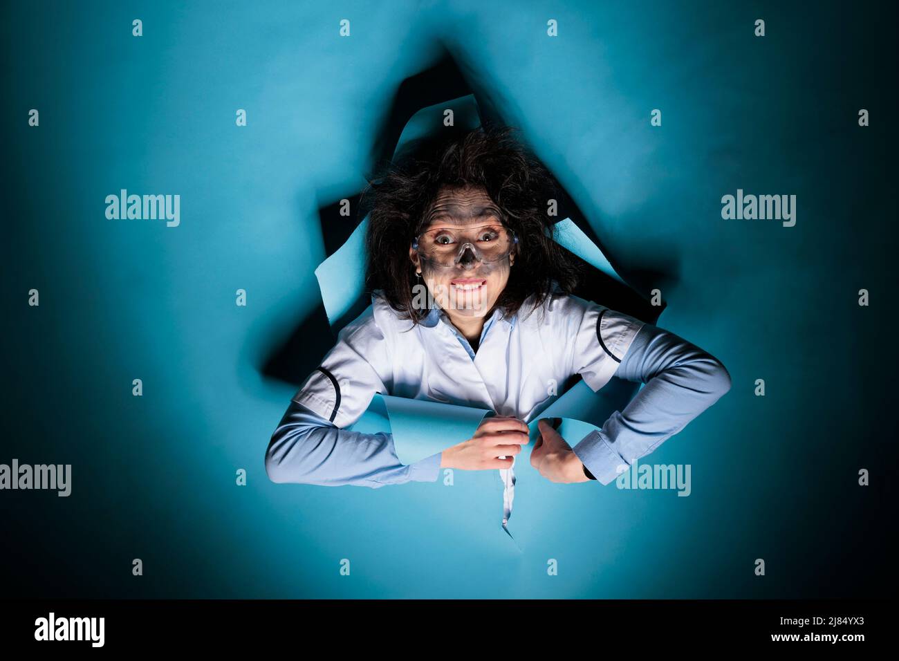 Portrait d'une femme folle et folle avec un regard et une apparence sordides après une explosion de laboratoire scientifique. Expert scientifique fou avec l'expression du visage amusante et les cheveux désordonnés. Banque D'Images