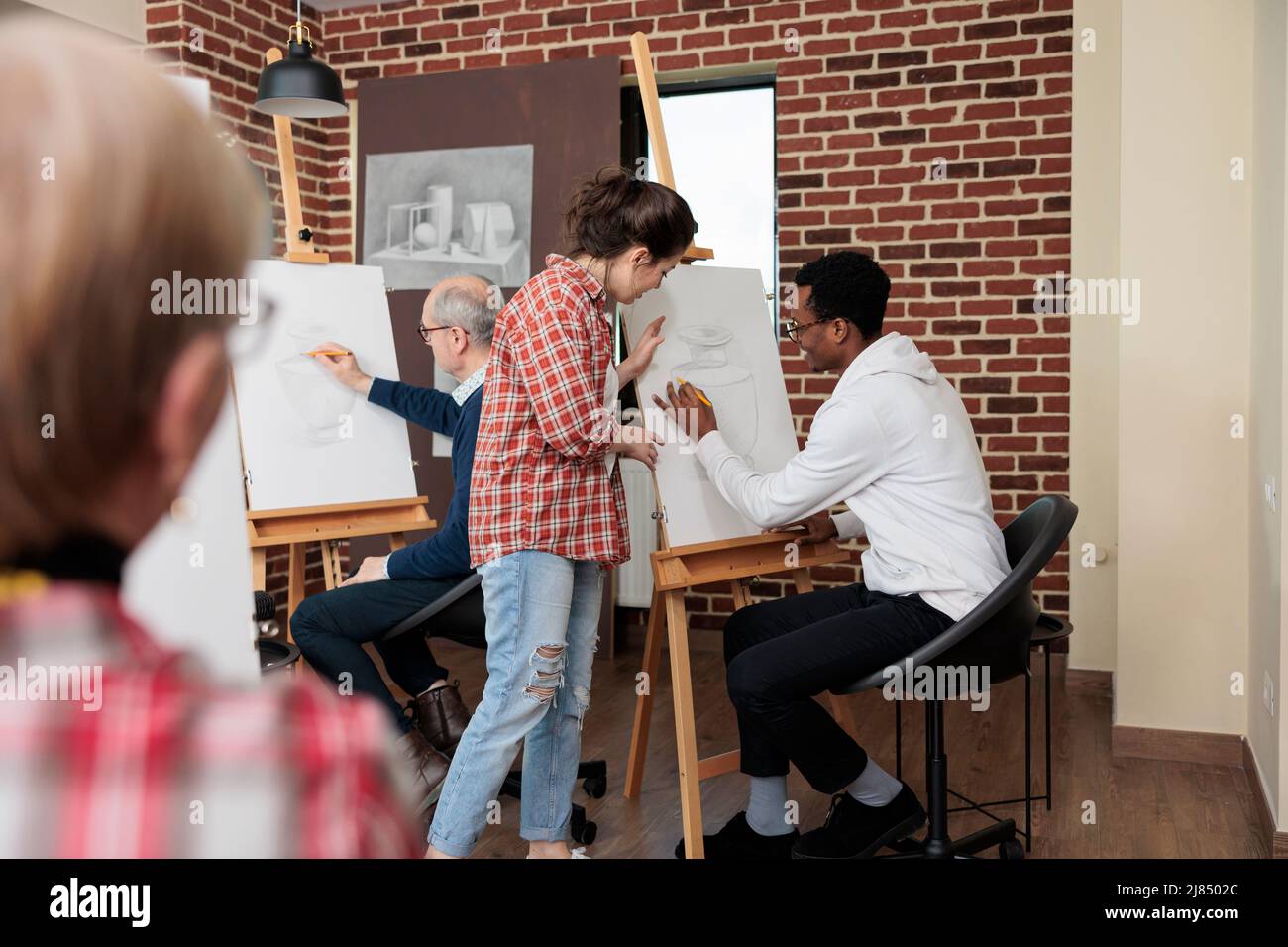 Professeur de classe expliquant le processus de croquis aux jeunes élèves pendant la leçon de créativité à l'école. Divers modèles de vase de dessin d'équipe sur toile blanche utilisant la technique d'illustration. Concept créatif Banque D'Images