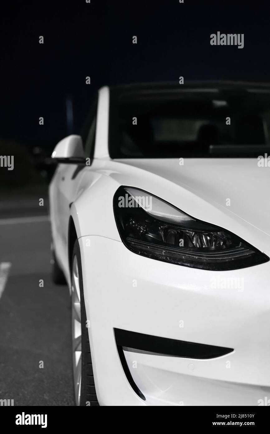 Phare avant, pare-chocs et extérieur de la voiture électrique blanche de la société Tesla Motors la nuit: Riga, Lettonie - 22 septembre 2021 Banque D'Images