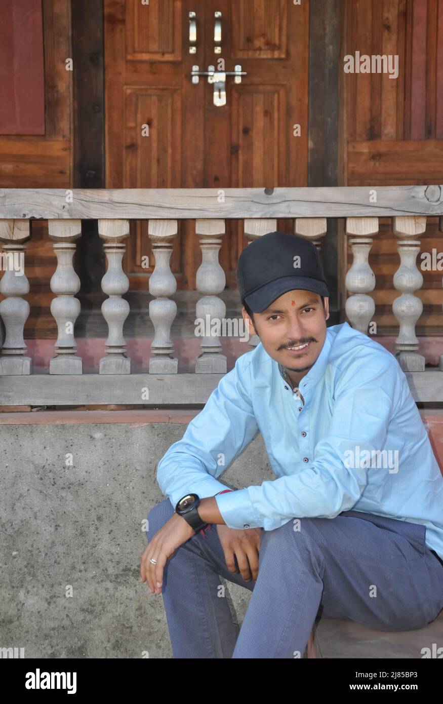Un jeune homme souriant portant une casquette en regardant l'appareil photo tout en étant assis sur les escaliers du temple Banque D'Images