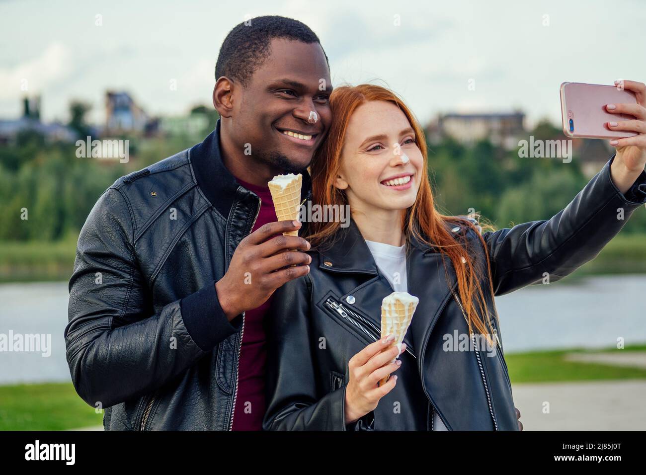 Couple multiethnique divers manger de la glace au printemps parc d'automne et faire selfie photo sur l'appareil photo de smartphone Banque D'Images