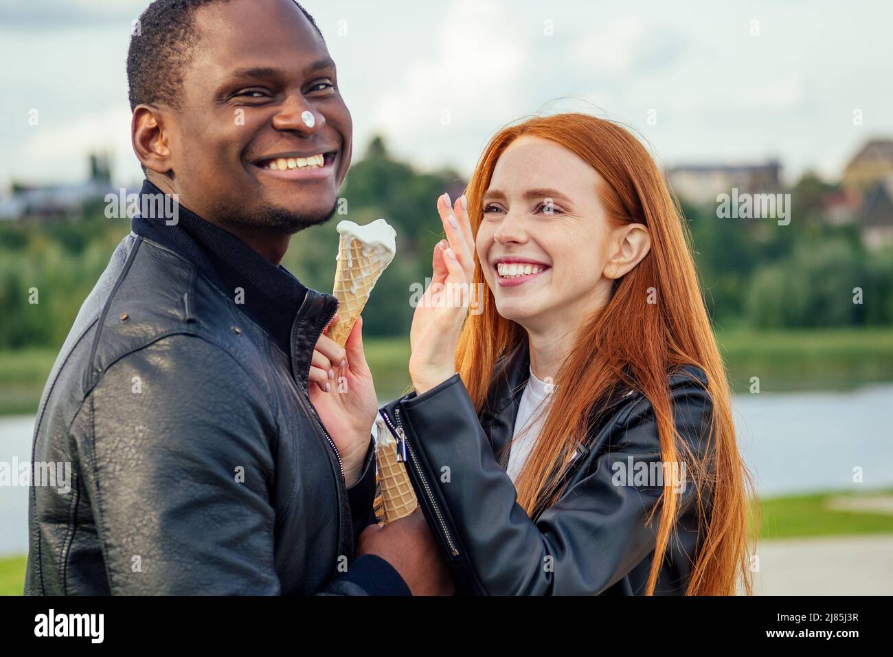 Couple multi-ethnique divers manger de la crème glacée dans le parc d'automne de printemps Banque D'Images