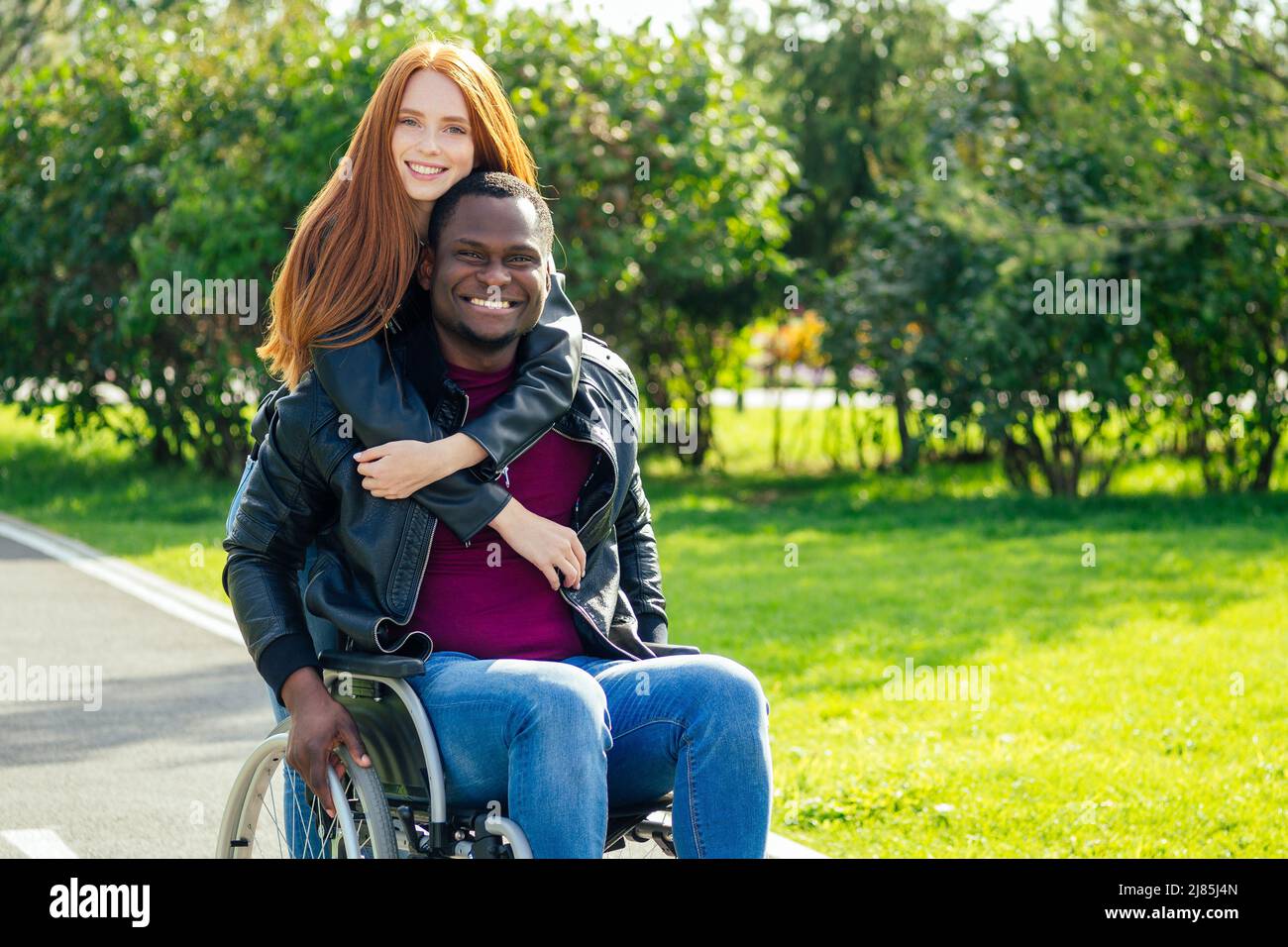 assurance voyage concept.international couple amoureux assis sur le banc dans le parc à côté d'une chaise de roue Banque D'Images