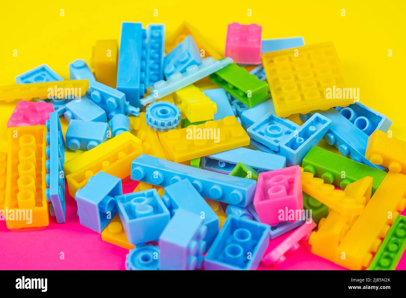 Jeu de blocs colorés, fond coloré, concept de jeu et d'apprentissage, jouets déversés pour enfants, blocs de construction, toile de fond jaune et rose, vue du dessus Banque D'Images