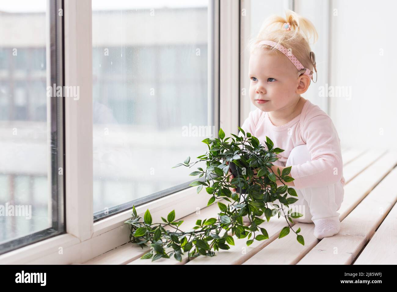 Implant cochléaire pour bébé. Enfant sourd avec prothèse auditive à la maison. Espace de copie un lieu de publicité Banque D'Images