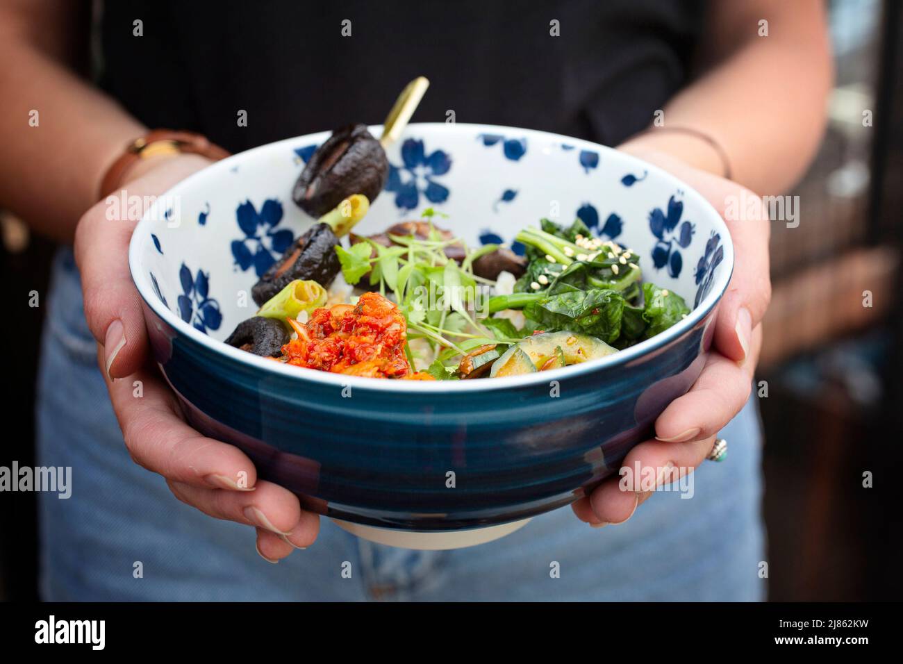 Les mains se berce un bol de nourriture japonaise Banque D'Images