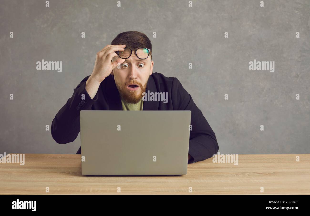 Homme effrayé ayant un problème avec l'ordinateur portable et regardant l'écran avec l'expression de visage choqué Banque D'Images