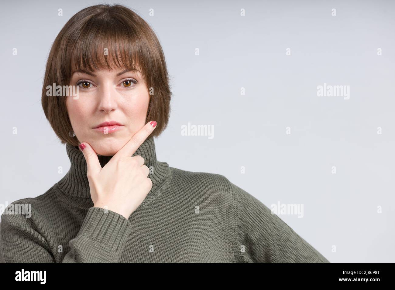 une jeune jolie femme dans un chandail vert pense Banque D'Images