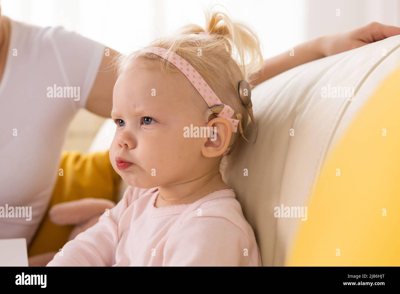 Bébé avec implants cochléaires s'amuser à la maison. Surdité et concept de technologie médicale. Banque D'Images