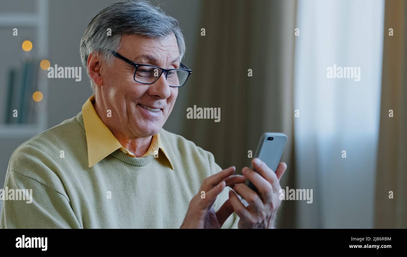 Âge mature mature 60s homme caucasien avec téléphone grand-père utilise l'application mobile à la maison achète la médecine en ligne brows sur le net écrit message à Banque D'Images