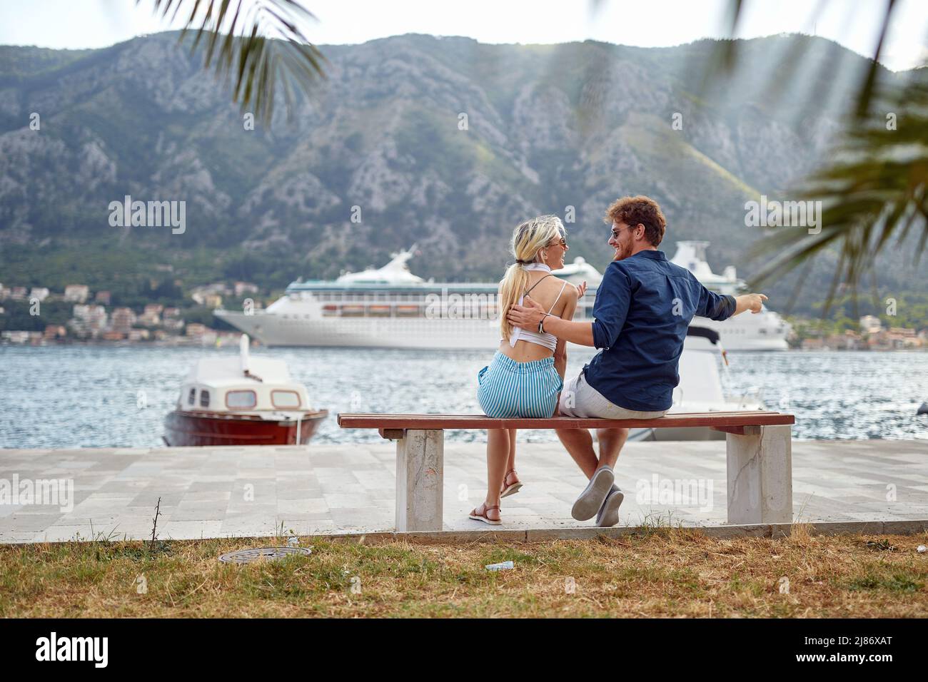 Un jeune couple amoureux assis sur le banc lors d'une belle journée sur le quai et bavardant. Amour, relation, vacances, mer Banque D'Images
