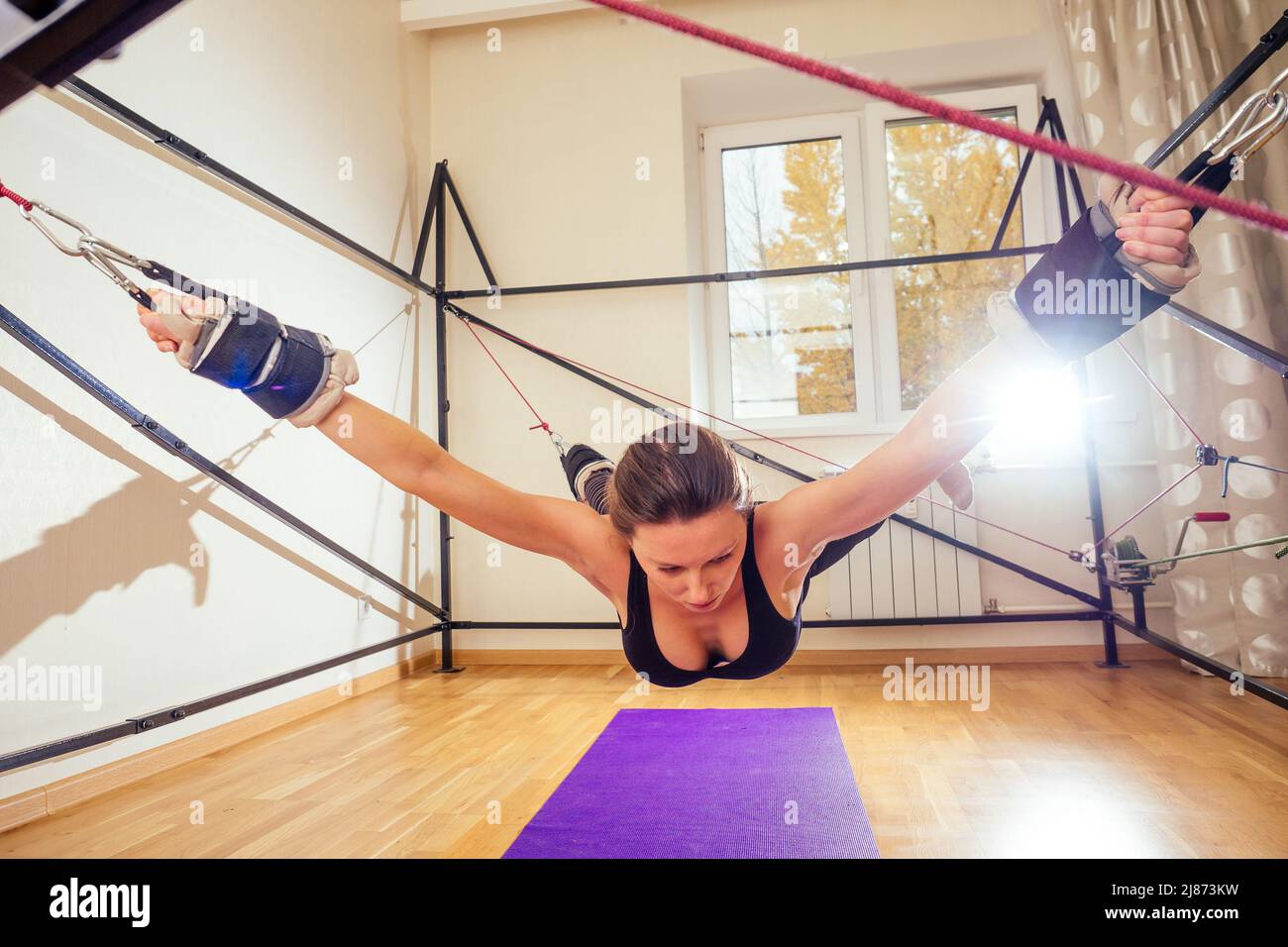 Jeune sportive femme caucasienne faisant des exercices d'étirement de muscle de corps complet entraînement sur l'aérobie extensible courroie dans la salle de gym, yogi mat Banque D'Images