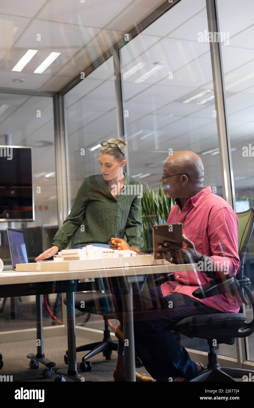 Architectes multiraciaux confiants discutant sur le modèle au bureau dans un lieu de travail moderne Banque D'Images