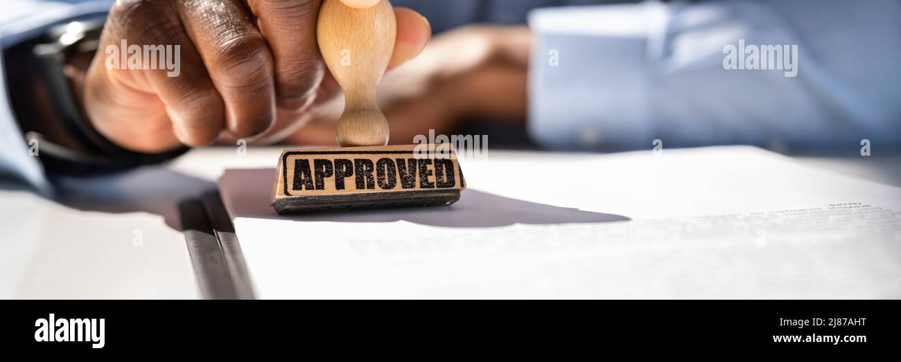 Close-up of a person's Hand Stamping avec timbre approuvé sur le document At Desk Banque D'Images