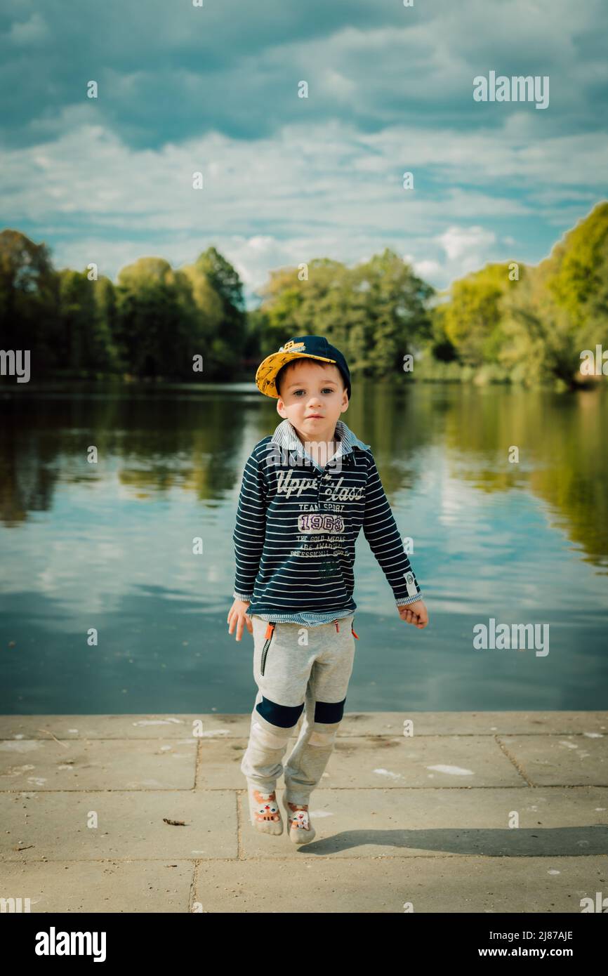 Un petit enfant se tient près d'un lac dans un parc en été Banque D'Images