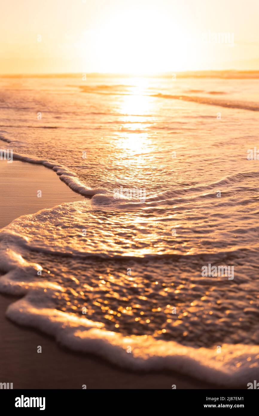 Vue panoramique de la lumière du soleil se reflétant sur le paysage marin et des vagues éclaboussant sur la rive contre un ciel clair Banque D'Images