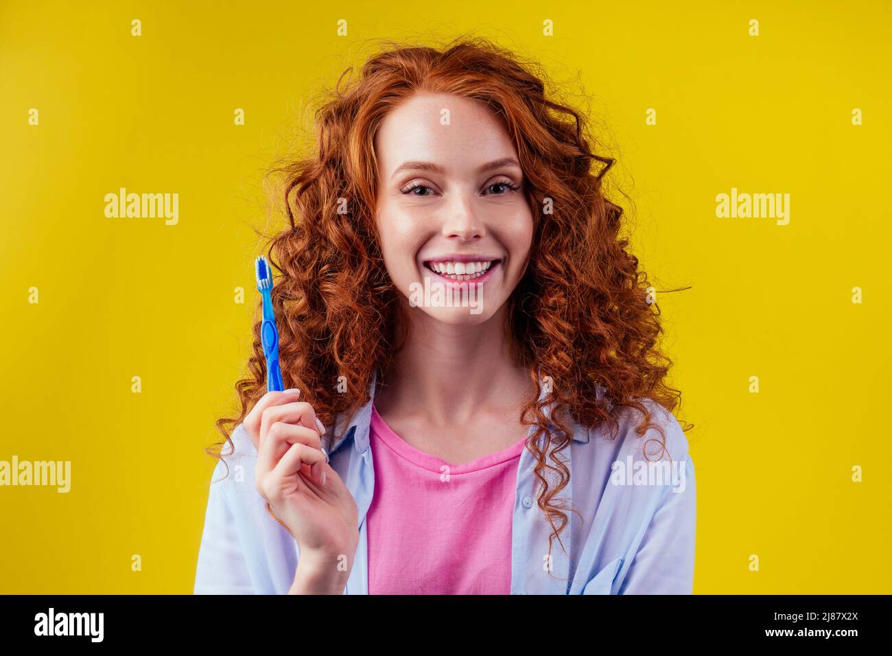 femme gingembre rougeâtre avec brosse à dents écologique et dentifrice sur fond jaune studio Banque D'Images
