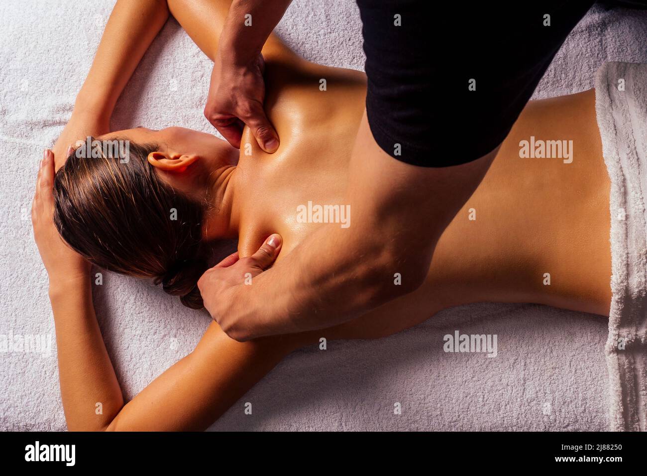 Masseuse mains faisant un massage du dos au client dans le centre de spa dans la pièce sombre Banque D'Images