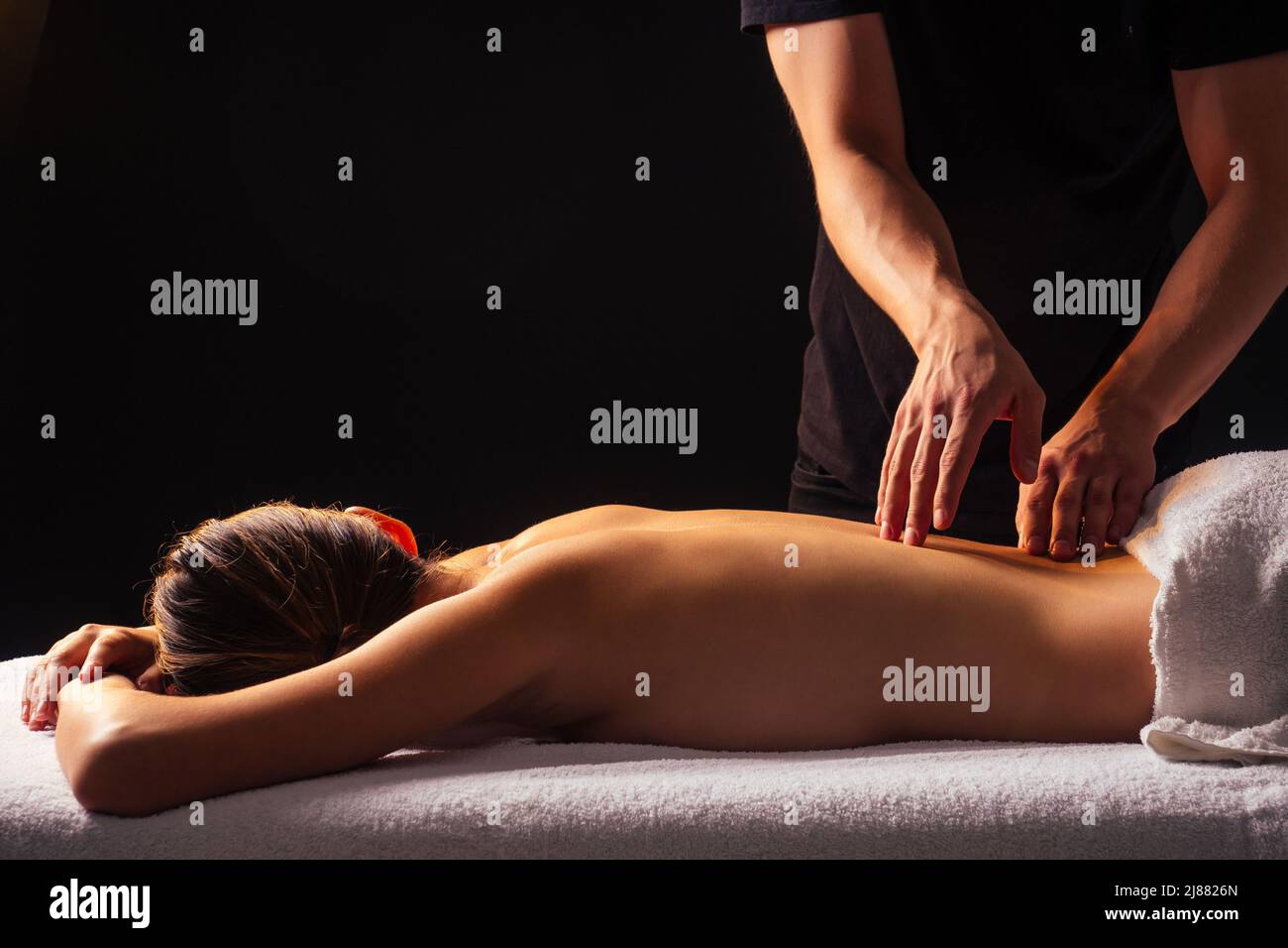 Masseuse mains faisant un massage du dos au client dans le centre de spa dans la pièce sombre Banque D'Images