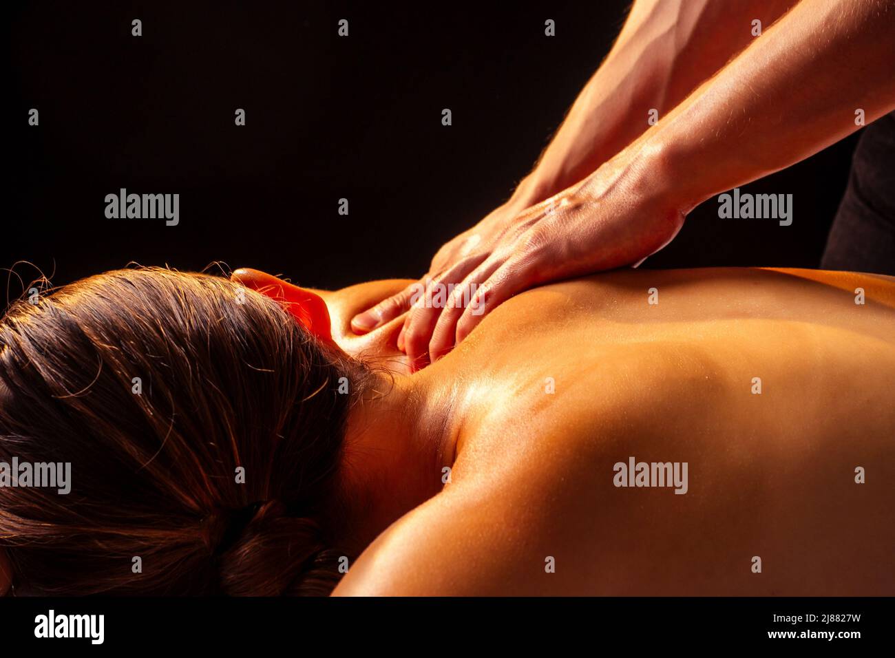 Mains de masseuse faisant le massage de panchakarma dos au client dans le centre de spa dans la pièce sombre Banque D'Images