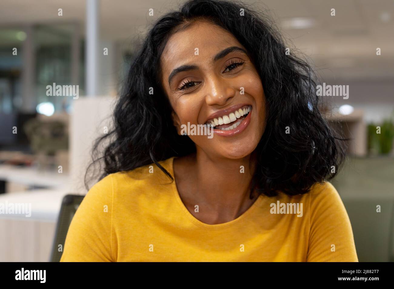 Portrait d'une jeune femme d'affaires multiraciale heureuse avec des cheveux noirs travaillant au bureau Banque D'Images