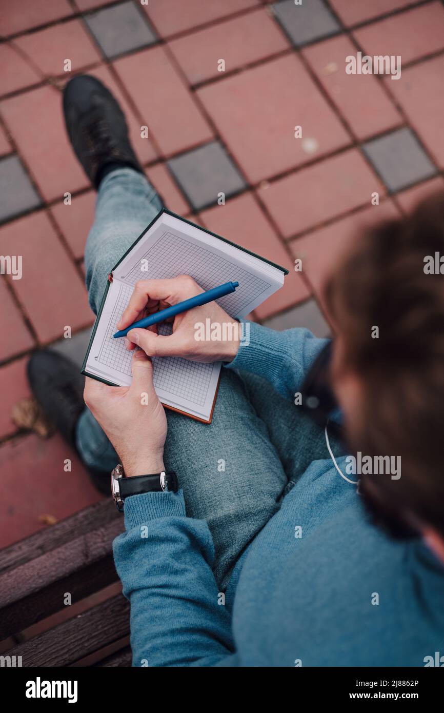 jeune gay hipster garçon avis des idées siting dans un parc et écouter de la musique par des écouteurs Banque D'Images