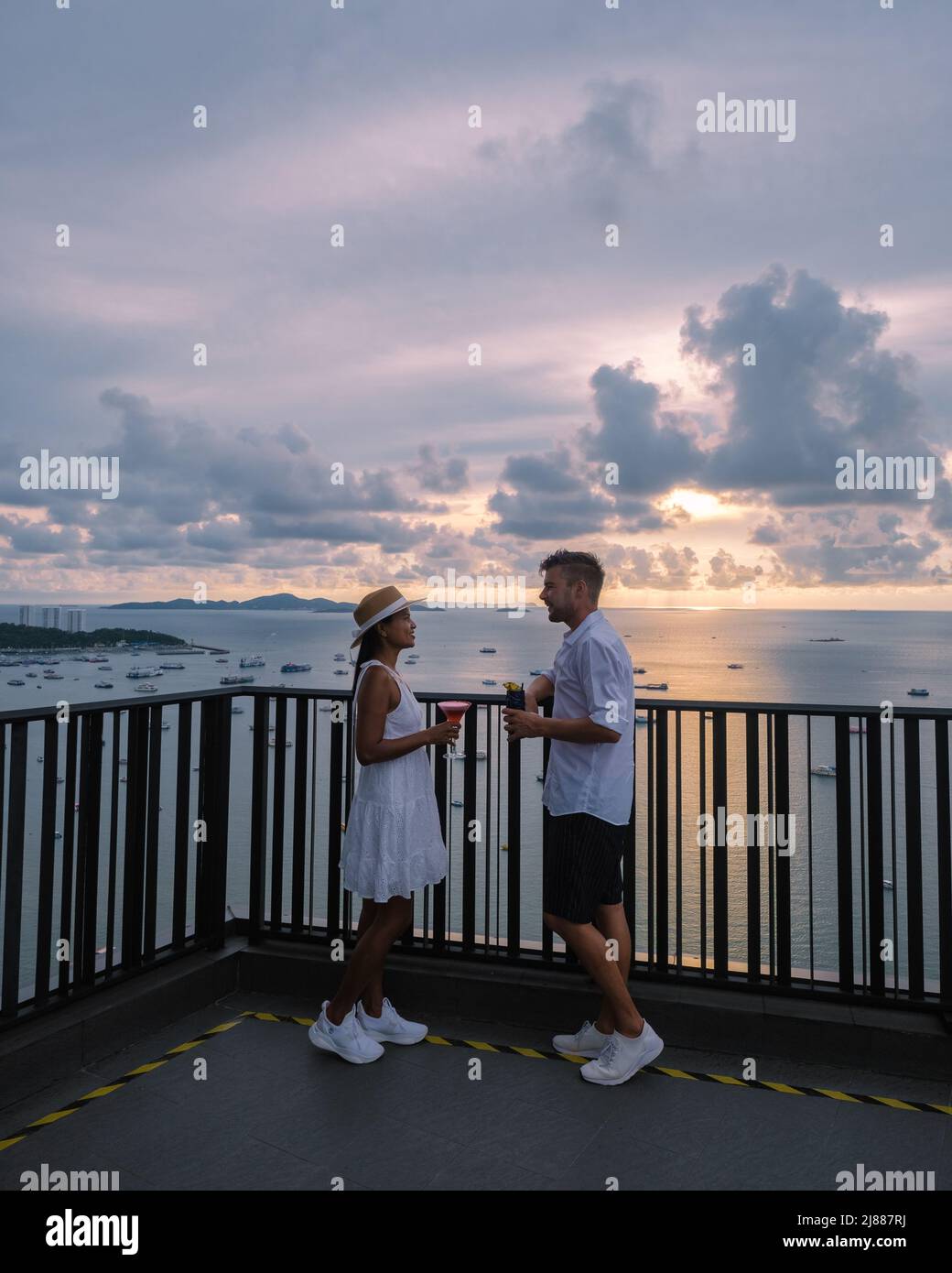 Vue depuis la terrasse du Hilton Sky Bar au coucher du soleil. Pattaya bar sur le toit Thaïlande, un couple homme, et des femmes regardant le coucher du soleil depuis un bar sur le toit Banque D'Images