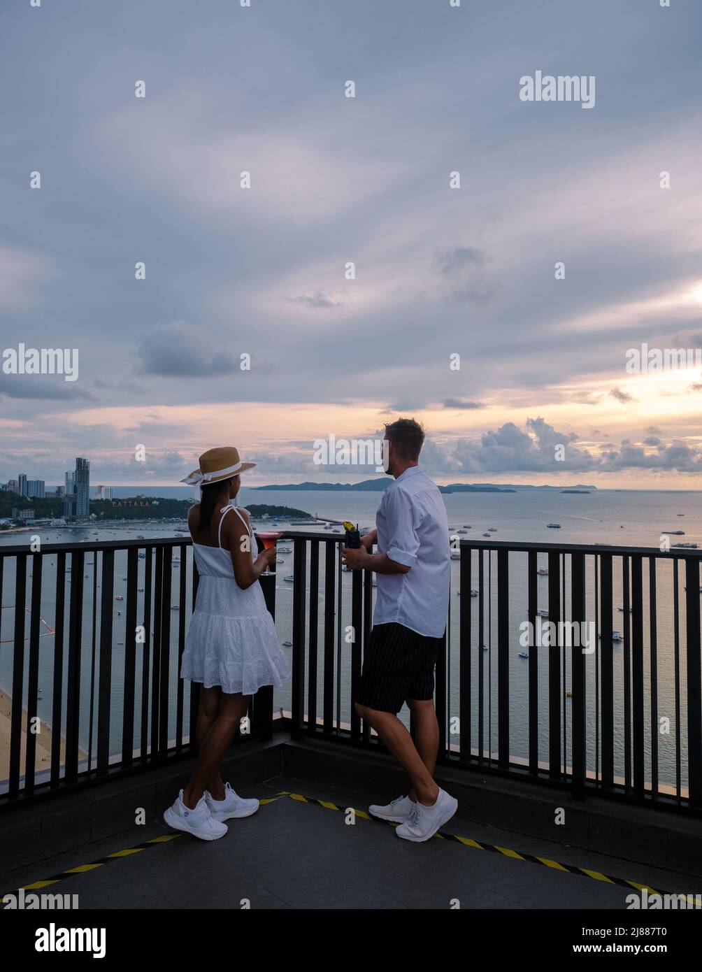Vue depuis la terrasse du Hilton Sky Bar au coucher du soleil. Pattaya bar sur le toit Thaïlande, un couple homme, et des femmes regardant le coucher du soleil depuis un bar sur le toit Banque D'Images