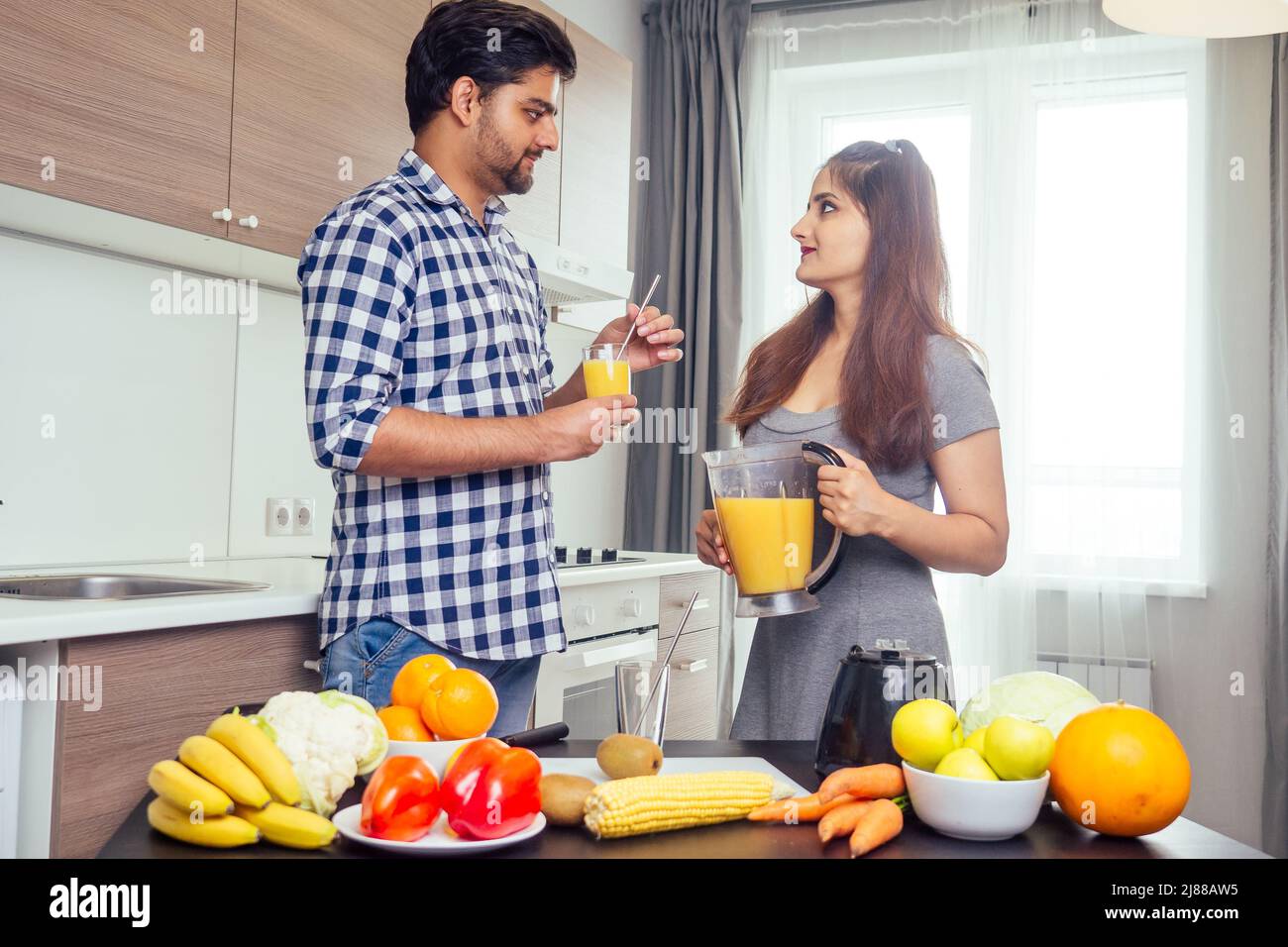 un style de vie sain et écologique.une femme indienne heureuse avec son mari qui fait du smoothie dans la grande cuisine Banque D'Images