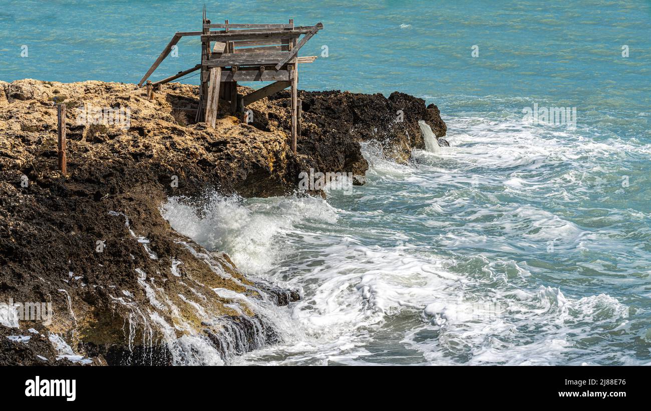 Ancien lieu de pêche sur un promontoire côtier dans le Gargano. Les vagues de la mer après la tempête se brisent violemment sur les rochers. Puglia Gargano Banque D'Images